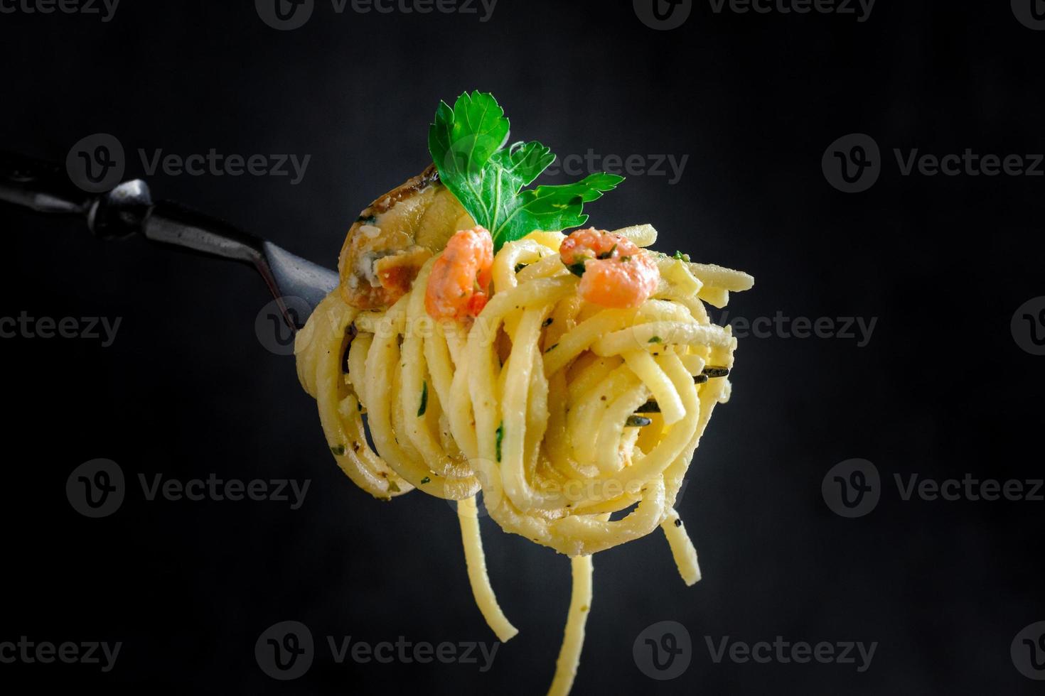 pasta med musslor och räkor på en gaffel på en mörk bakgrund foto