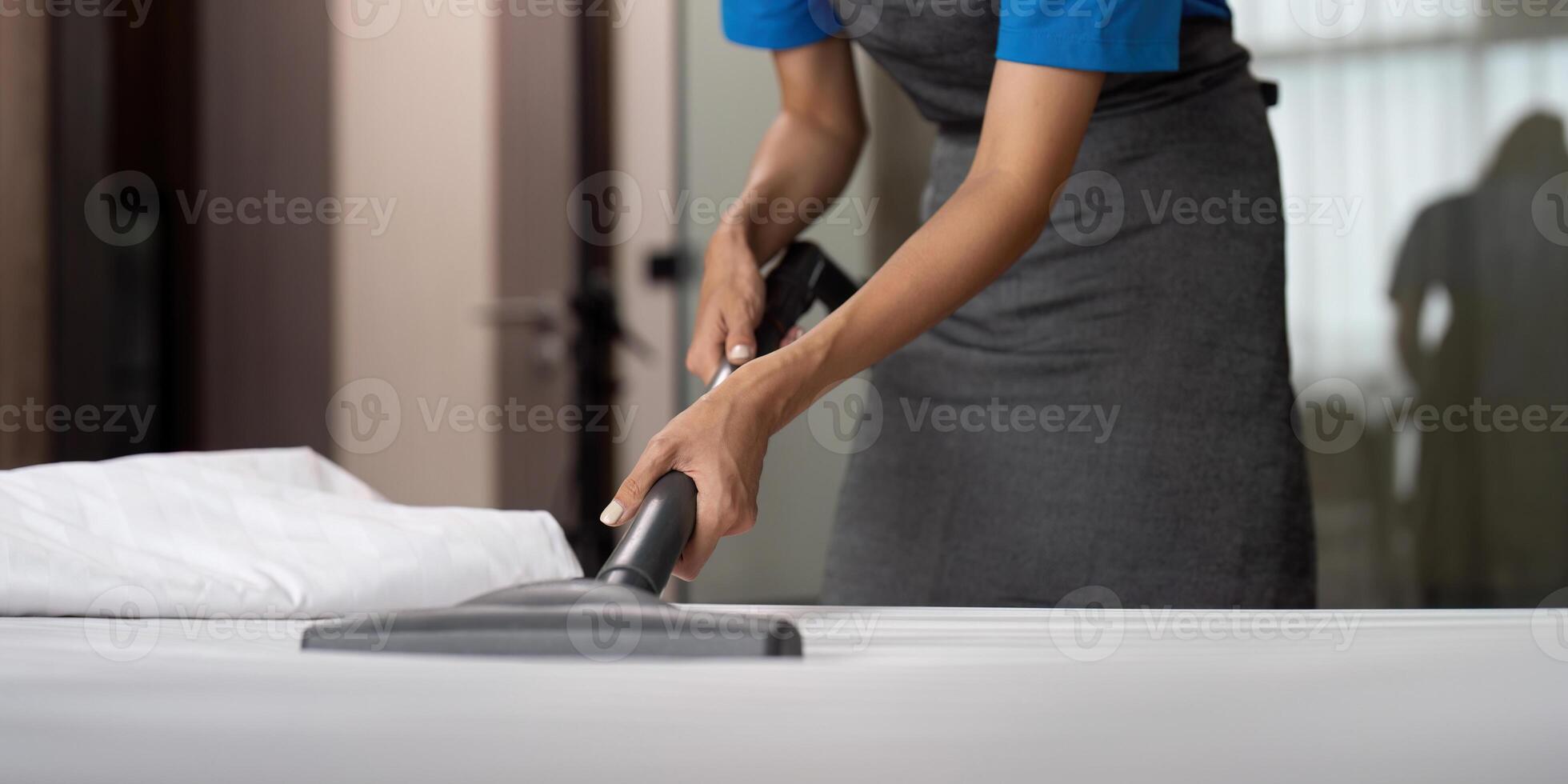 rengöring service anställd avlägsnande smuts från med professionell Utrustning. kvinna hushållerska rengöring de madrass på de säng med Vakuum rengöringsmedel foto