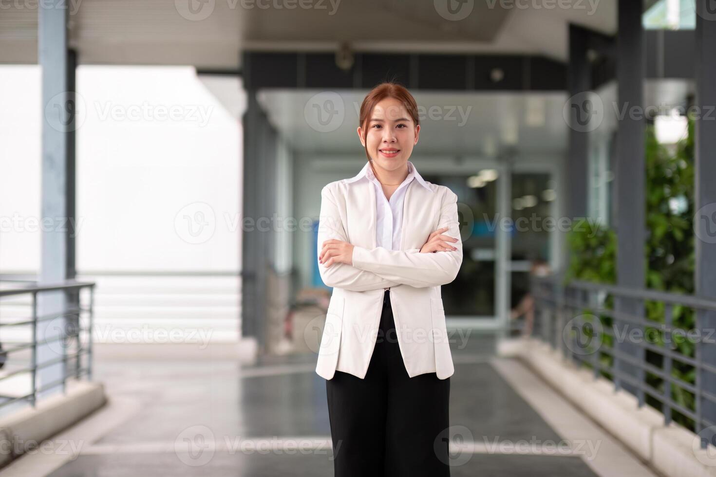 ung Lycklig leende professionell företag kvinna asiatisk, Lycklig självsäker positiv kvinna entreprenör stående på gata vapen korsade, ser på kamera foto