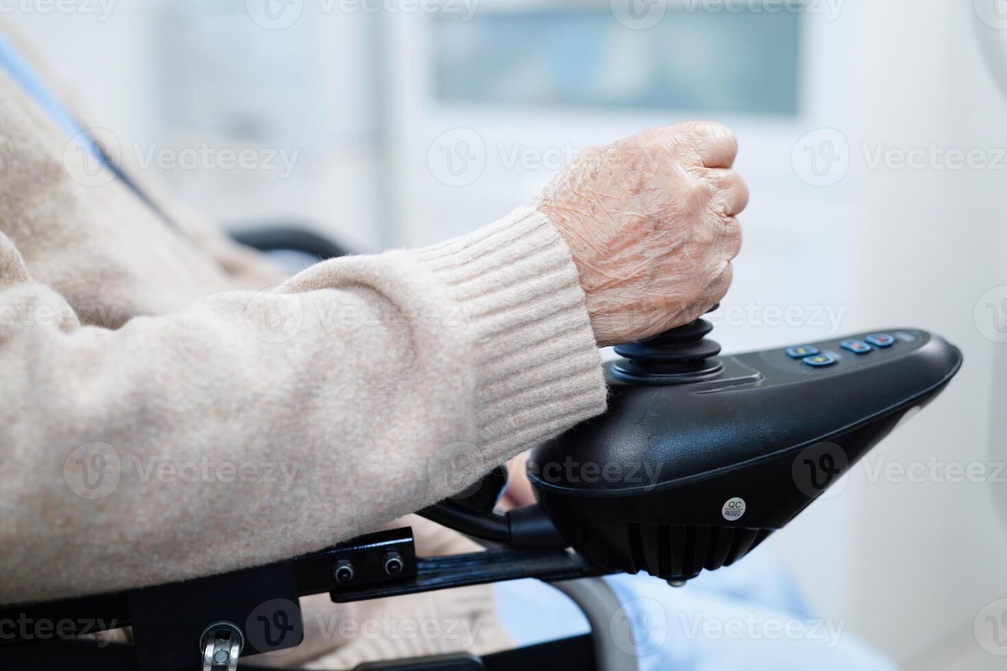 asiatisk äldre handikapp kvinna patient använda sig av joystick elektrisk rullstol i sjukhus. foto
