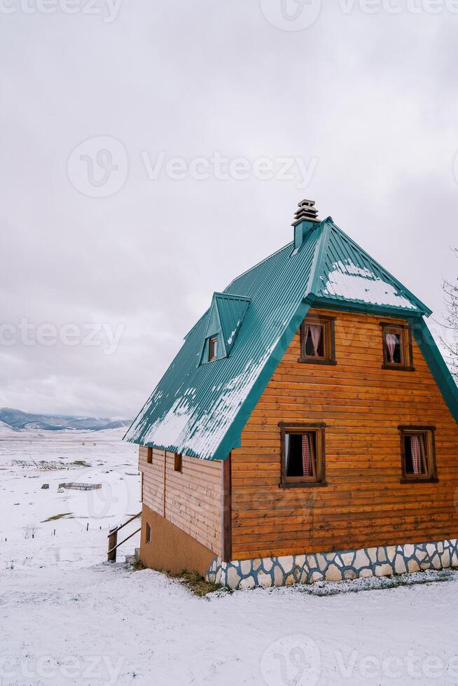 tvåvånings trä- stuga med en grön tak i en snöig berg dal foto