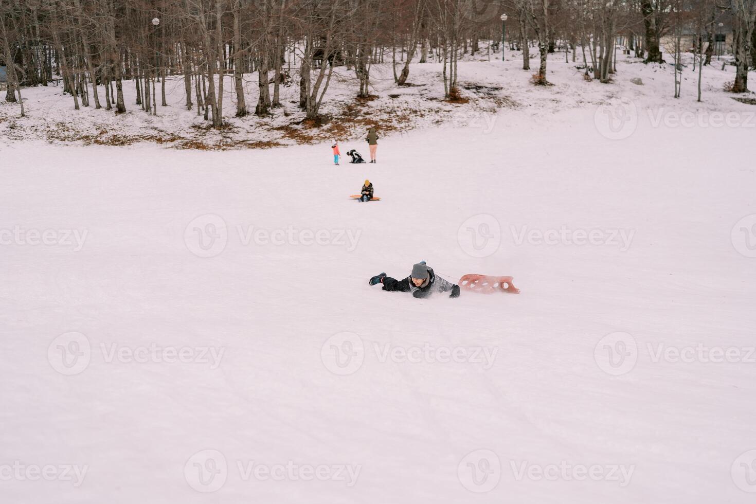 ung kvinna föll av de kälke och lögner på henne mage i de snö, ser bort foto