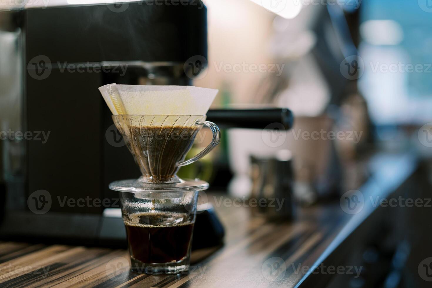 kaffe droppande in i en glas genom en filtrera i en Häll i över kaffe tillverkare på en tabell foto