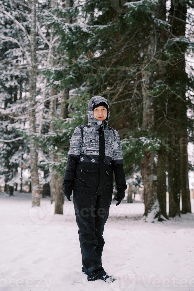 leende ung kvinna stående i snöig skog foto