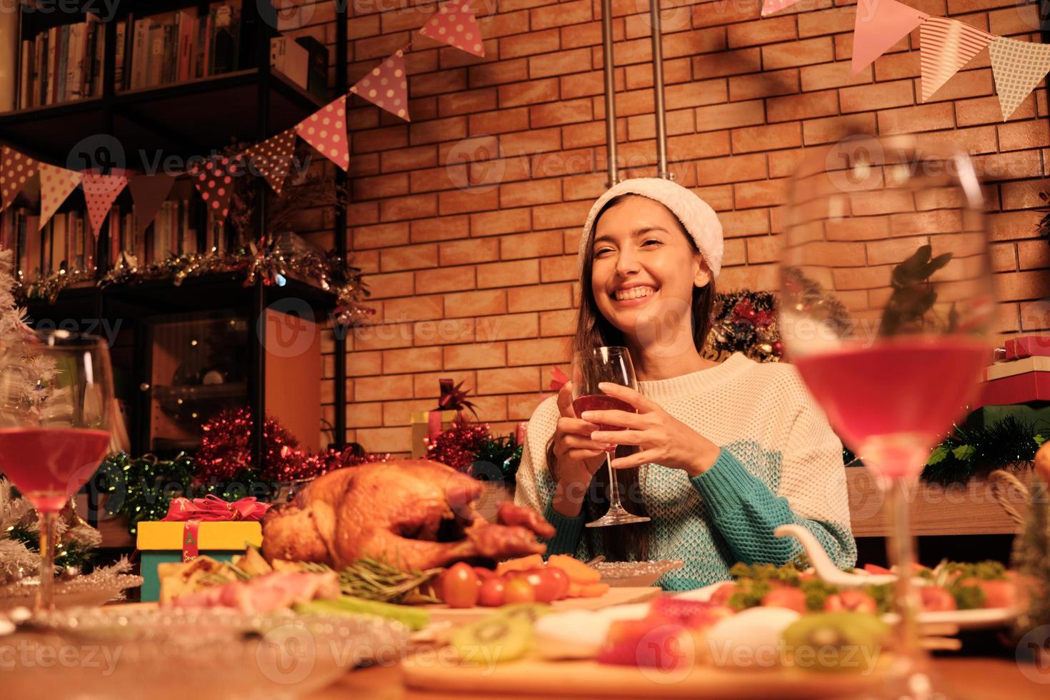 ung kaukasisk kvinna lycka leende på en diner med speciell mat som rostad kalkon och vin i julfest i matsalen dekorerad för glada festivaler och gott nytt år. foto