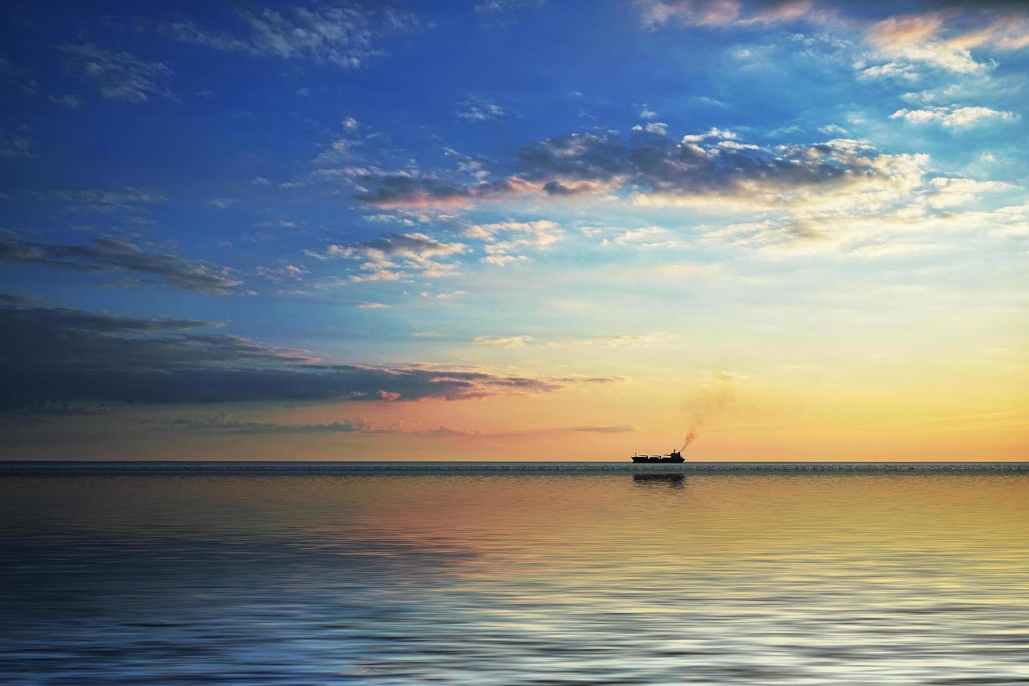 ett ensamt skepp vid horisonten i havet vid solnedgången. foto