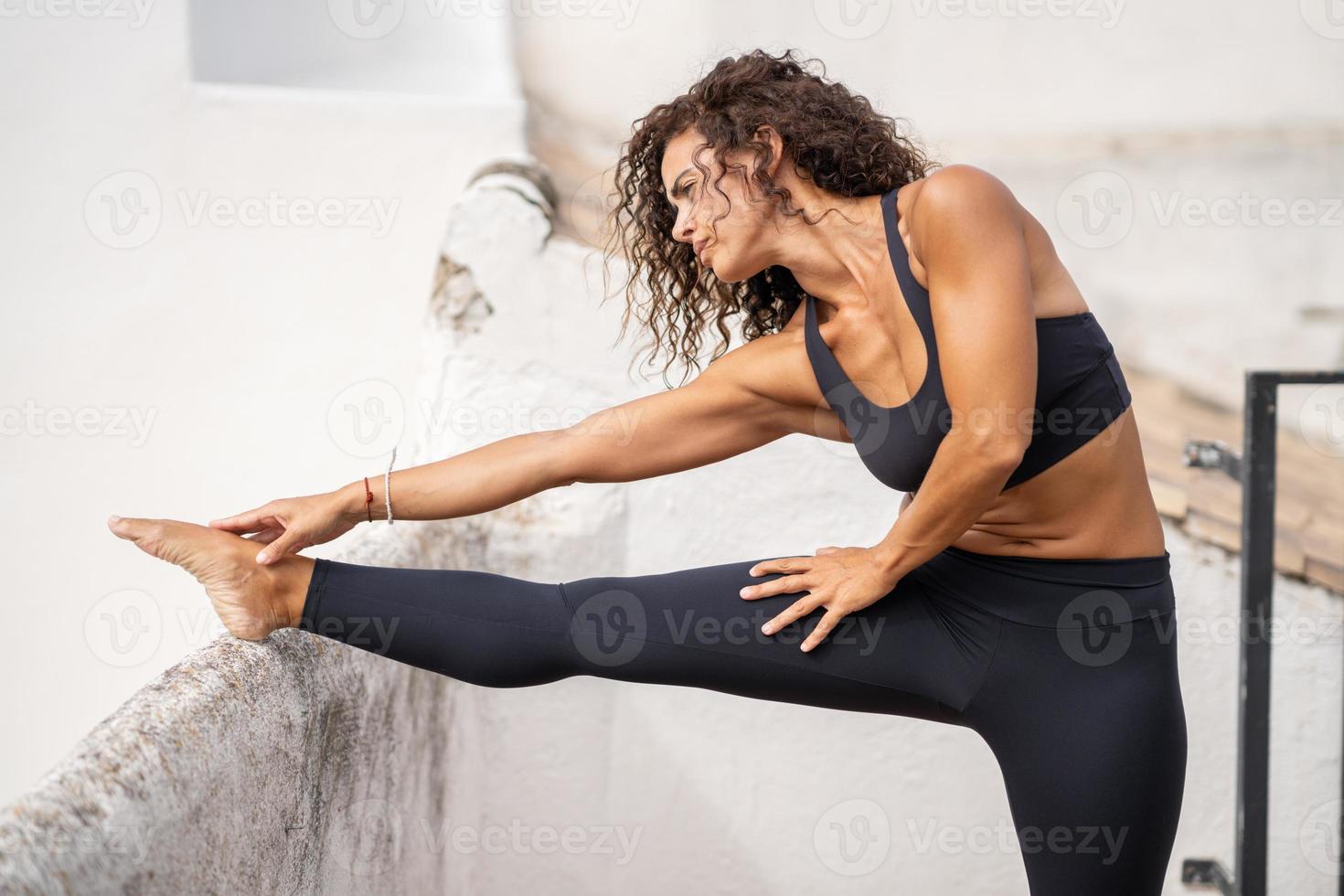 medelålders kvinna med fitness kropp tränar på terrassen i hennes hus foto
