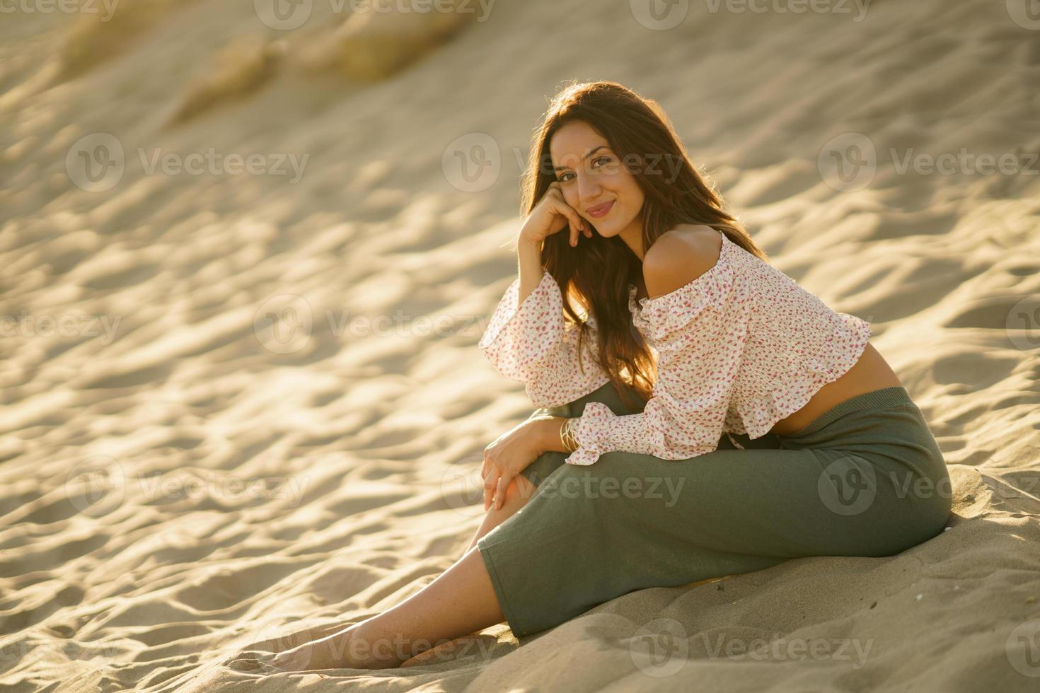 attraktiv kvinna sitter på sanden på stranden foto