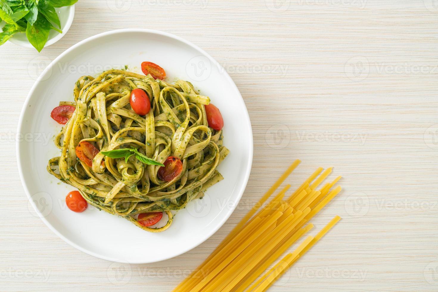 fettuccine spaghetti pasta med pestosås och tomater foto