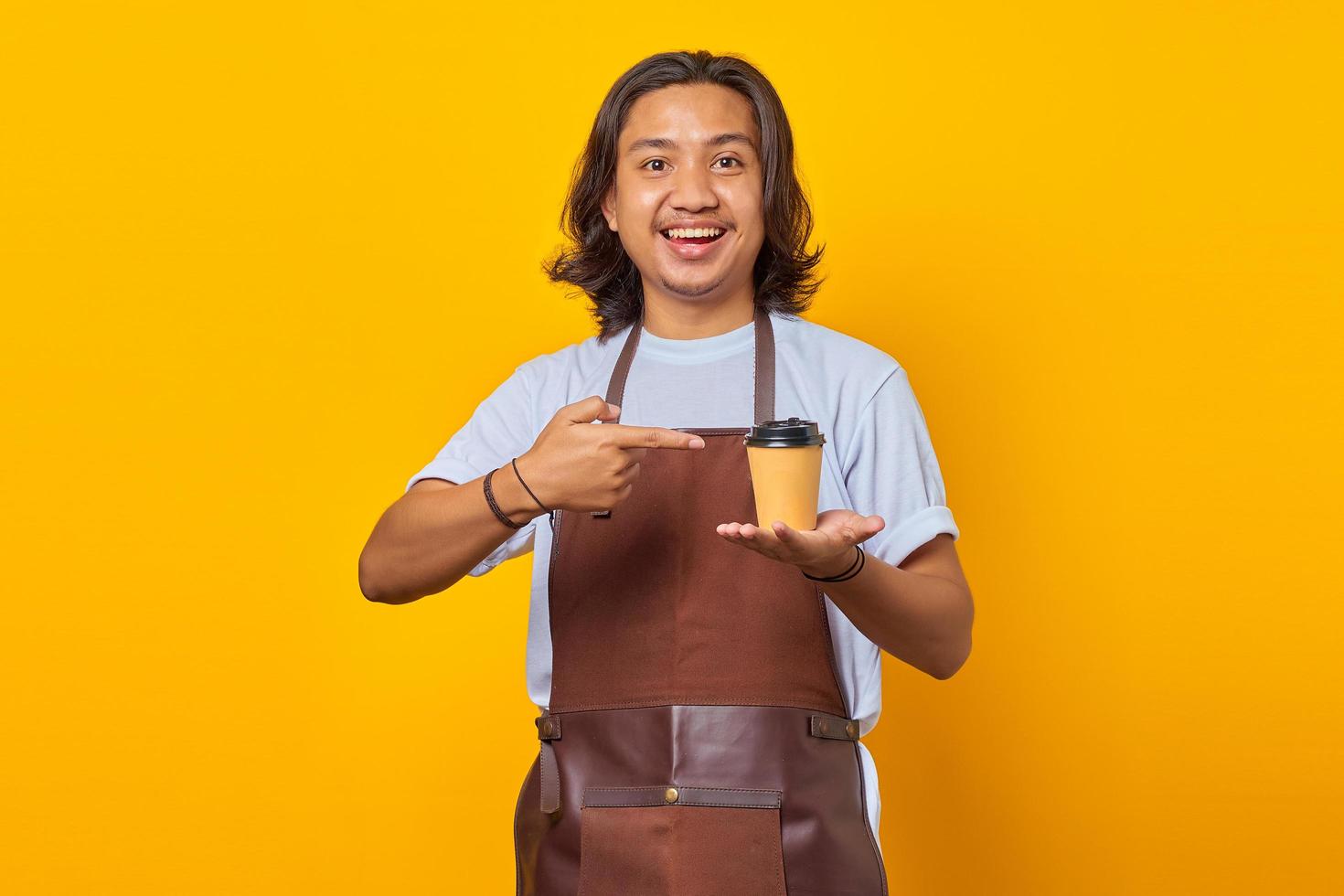 porträtt av positiv glad man håller pappersmugg med finger visar försäljning rabatt över gul bakgrund foto