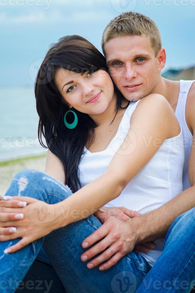 kille och en tjej i jeans och vita t-shirts på stranden foto
