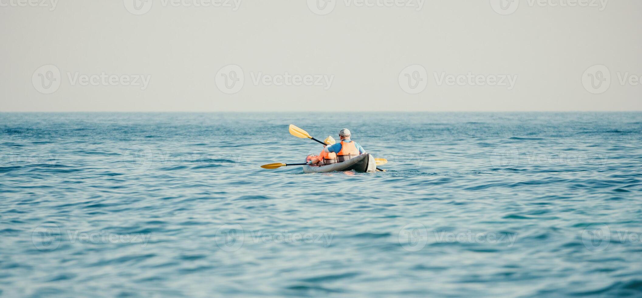 Lycklig par kajaker i ett uppblåsbar kajak på de hav på solnedgång. par kanotpaddling i de hav nära de ö med berg. människor Kajakpaddling i liv jackor segla. tillbaka se foto
