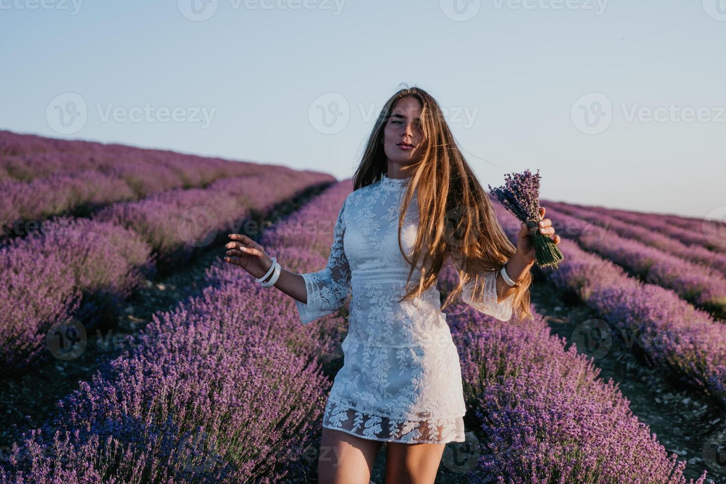 kvinna lavendel- fält. Lycklig sorglös kvinna i en vit klänning gående i en lavendel- fält och lukta en lavendel- bukett på solnedgång. idealisk för värma och inspirera begrepp i reslust och resa. foto