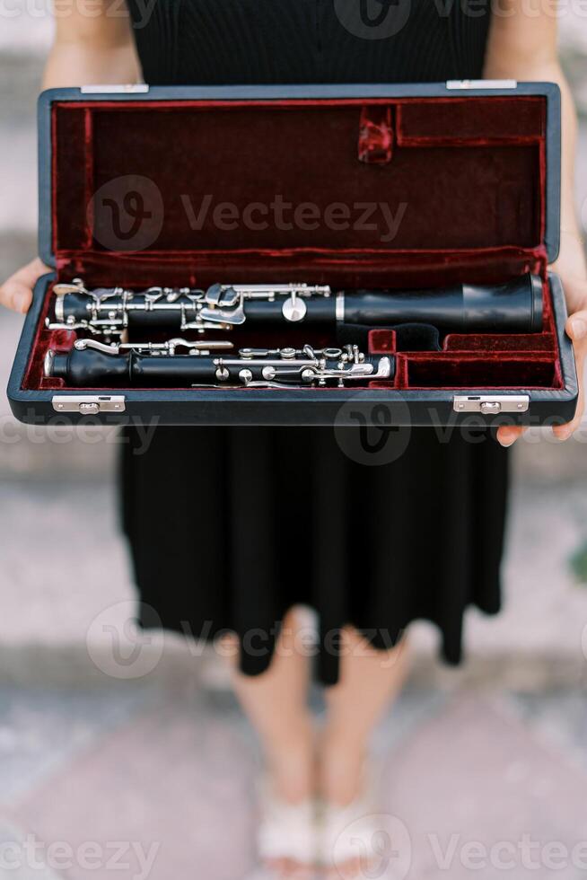 tjej-musiker innehar en klarinett i en fall i henne händer. beskuren. ansiktslös foto