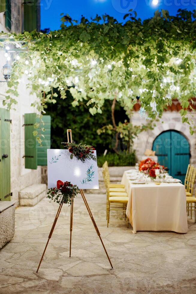 bröllop Välkommen tecken på en stativ dekorerad med blommor nära de uppsättning festlig tabell foto