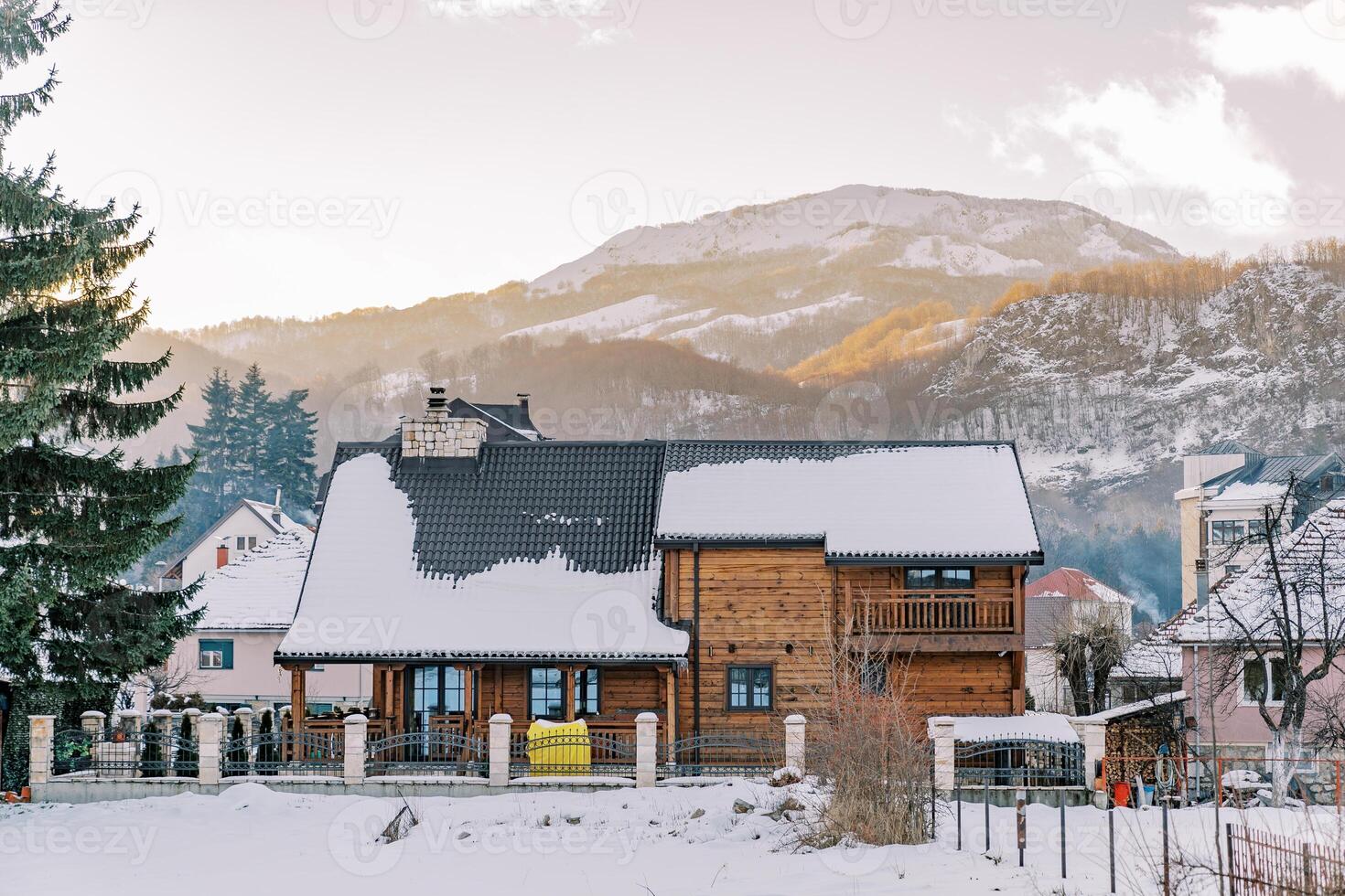 tvåvånings trä- stuga i en snöig by på de fot av de bergen foto