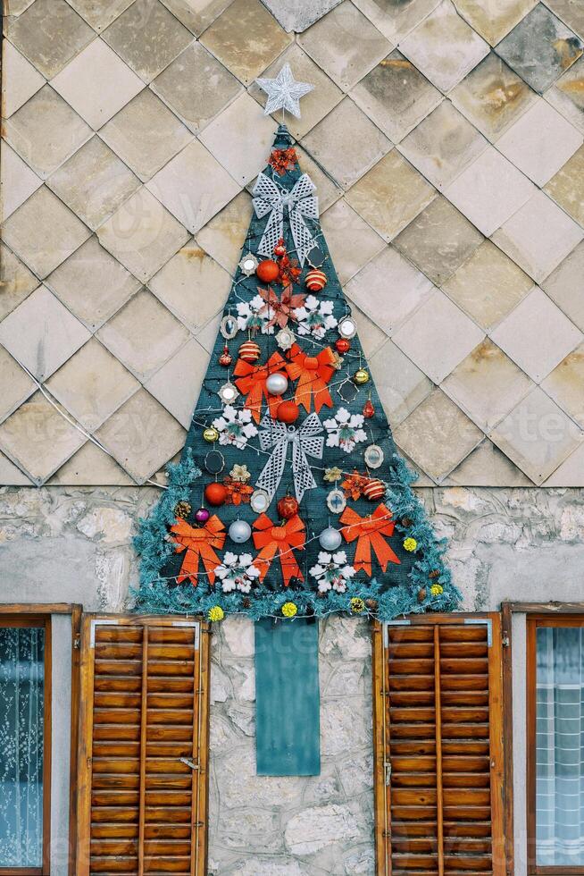 känt jul träd med röd bågar och kransar hänger på de vägg av de hus foto