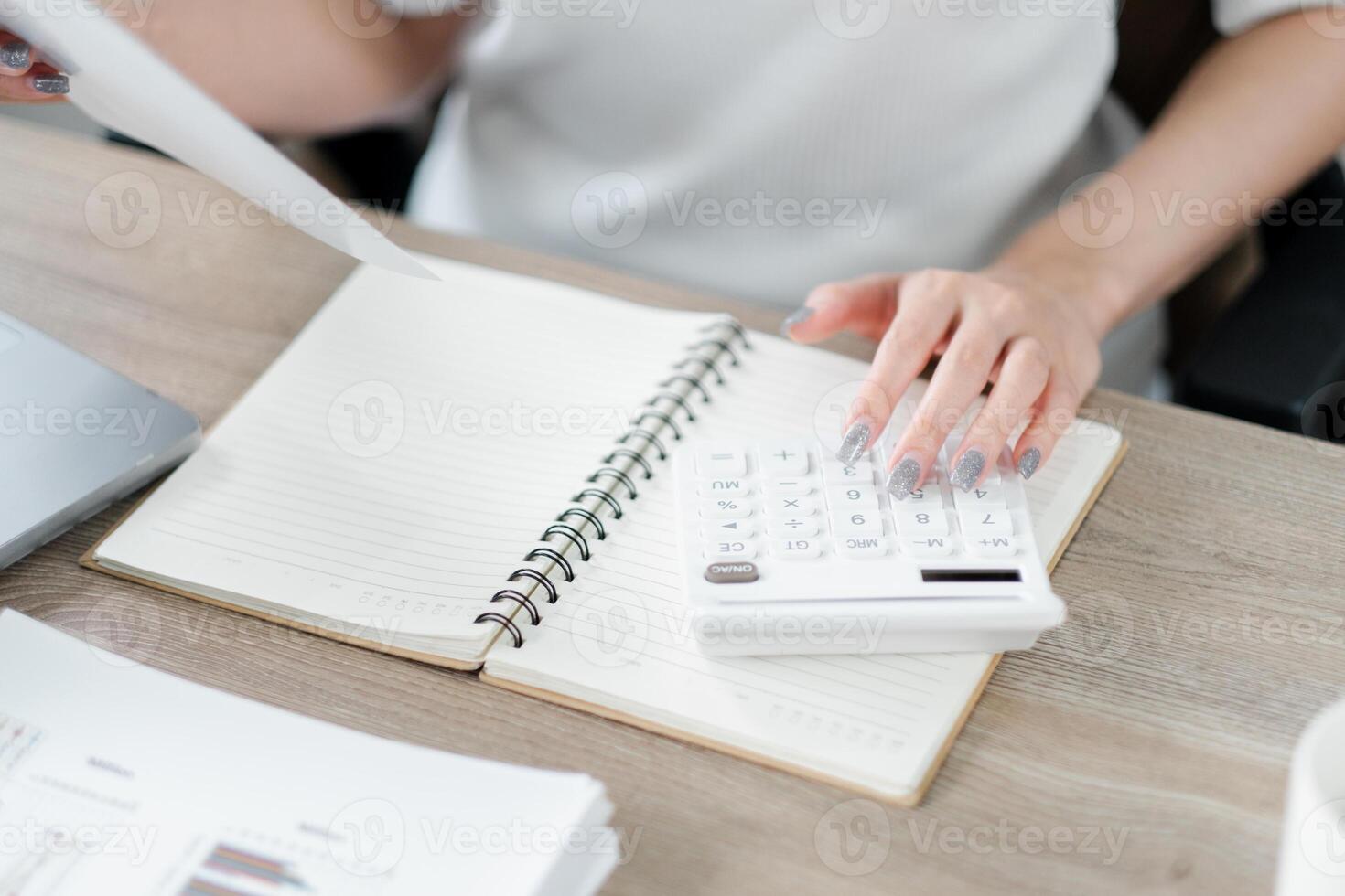 närbild av en professionella händer använder sig av en kalkylator på en skrivbord med pappersarbete. foto