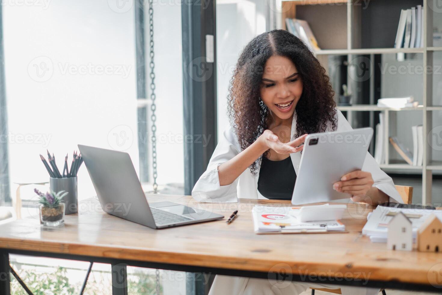 animerad affärskvinna engagerad i en video ringa upp, gestikulerar uttryckligen medan innehav en läsplatta i henne modern kontor. foto