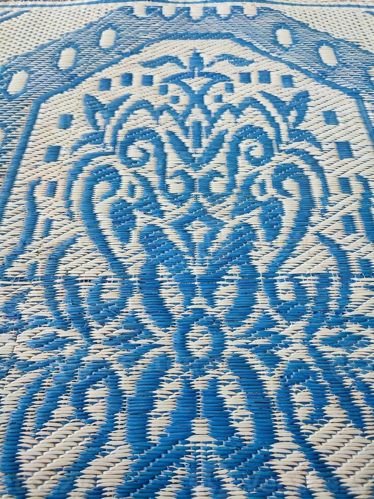 blå och vit vävd matta med motiv mönster på den foto