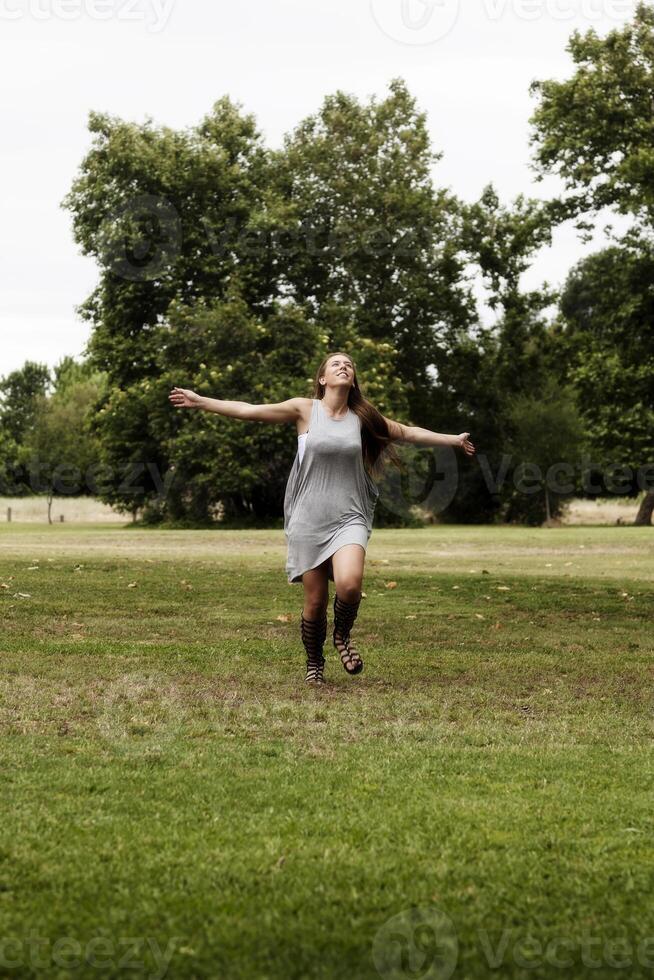 ung caucasian kvinna löpning på grön gräs vapen utsträckt foto