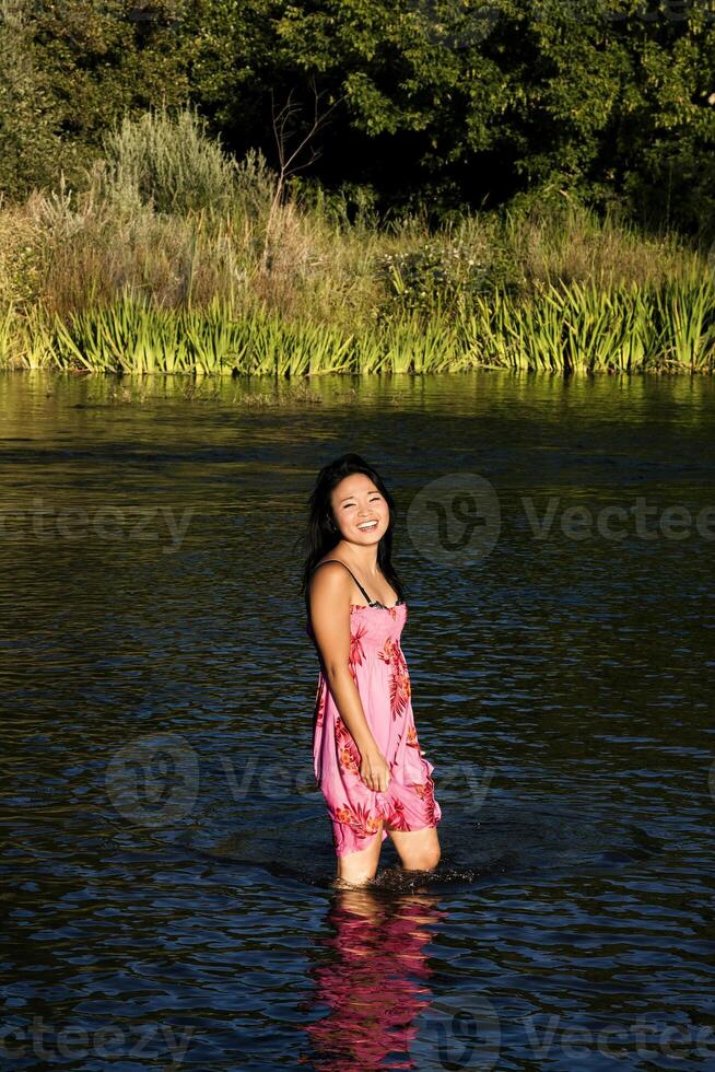 ung japansk kvinna stående i flod leende våt klänning foto