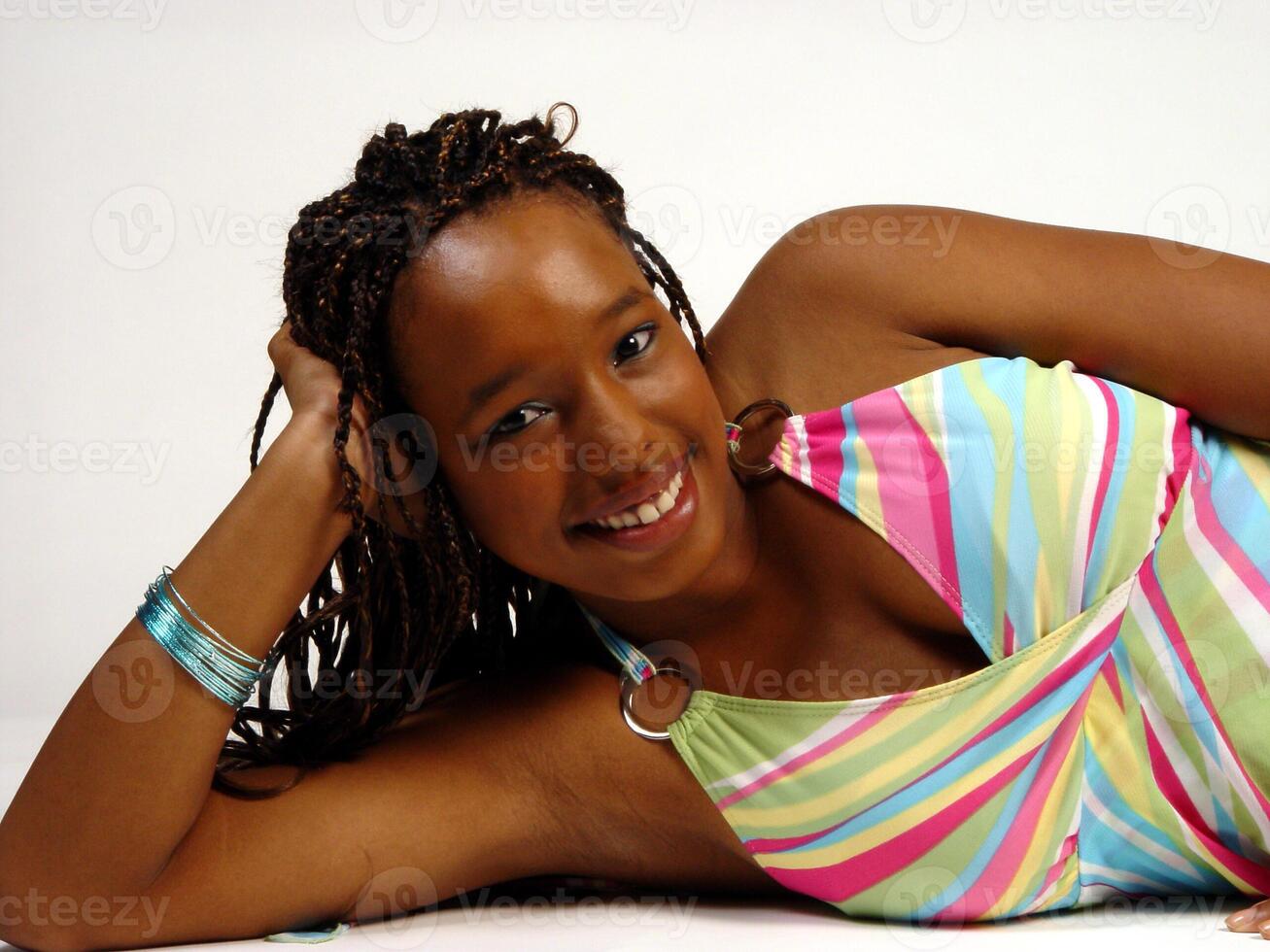 afrikansk amerikan tonåring flicka liggande och leende färgrik topp foto