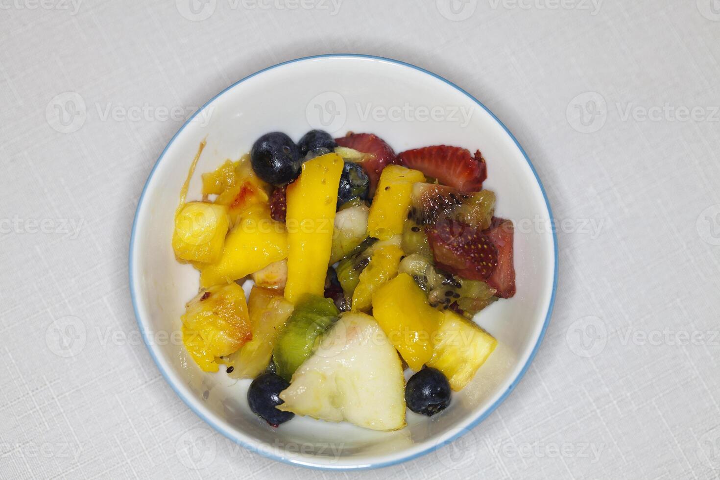 skära upp blandad frukt sallad i skål på tabell foto