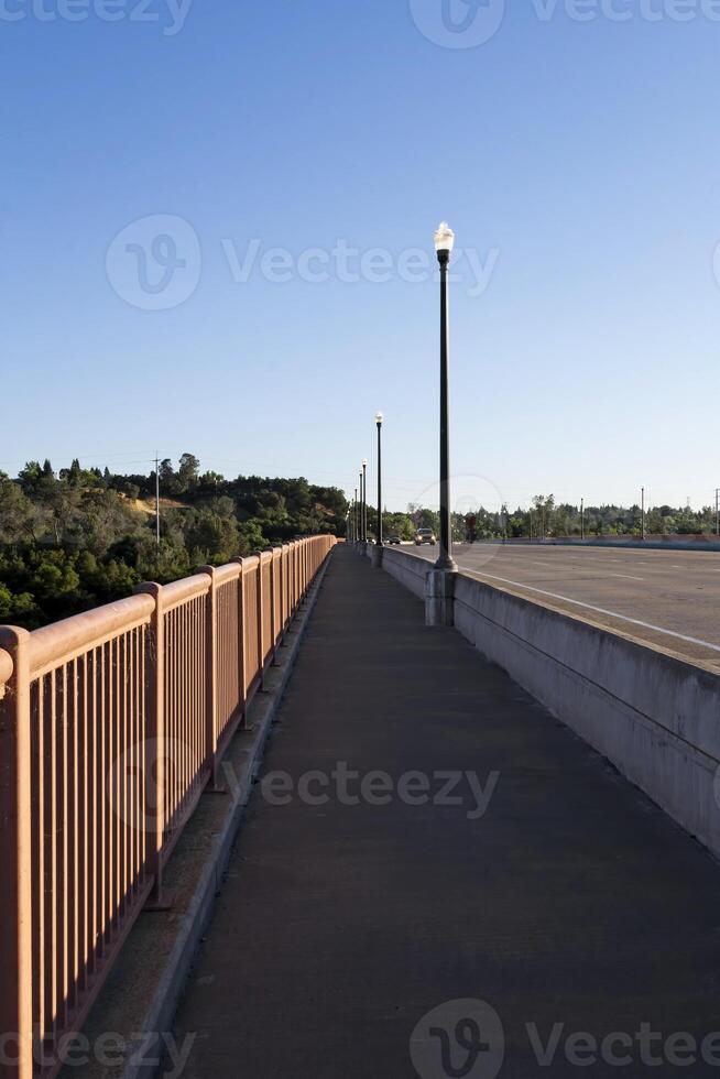 tömma fotgängare gångväg över bro morgon- blå himmel foto