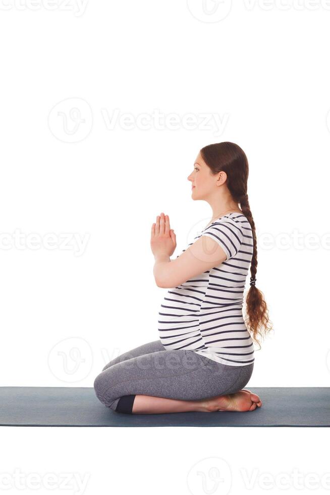 gravid kvinna håller på med yoga asana virasana isolerat på vit foto