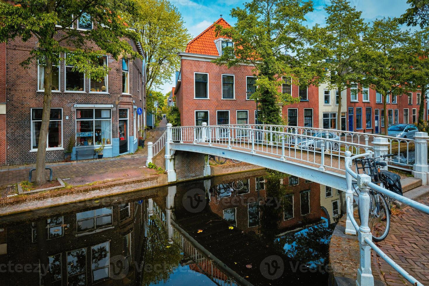 cykel på bro och kanal med bilar parkerad längs i delft gata foto