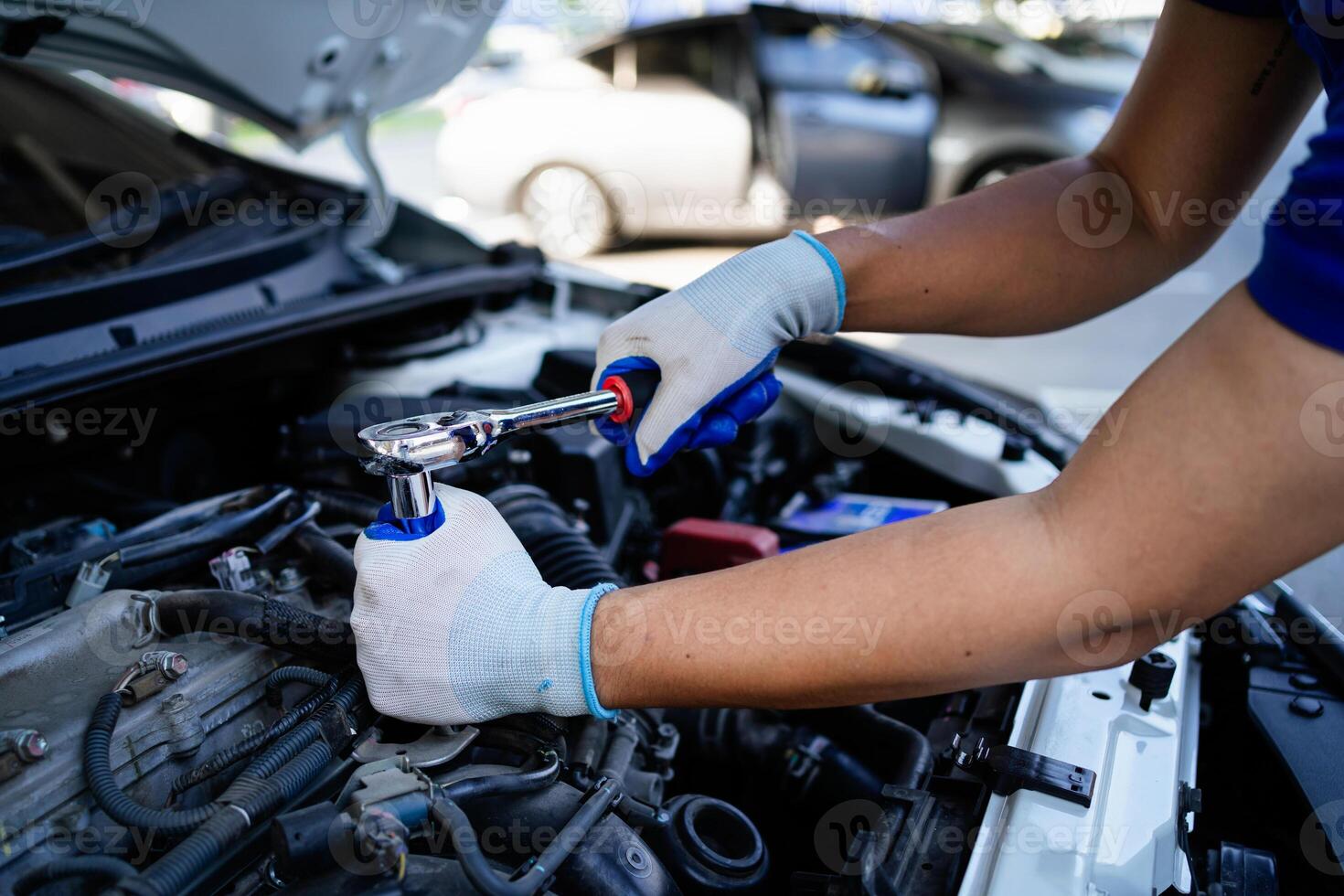 en mekaniker är arbetssätt på en bil motor, använder sig av en rycka till lossa en bult. begrepp av fokus och bestämning som de mekaniker Arbetar till fixera de bil foto