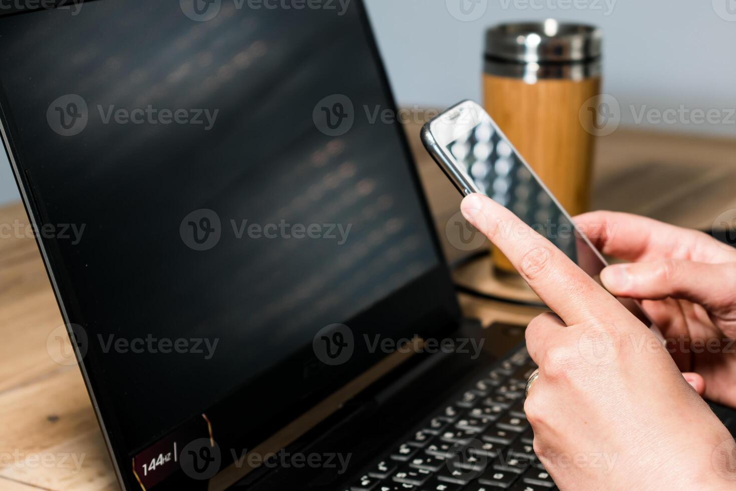 kvinna använder sig av mobil telefon i de kontor med en bärbar dator och en kaffe foto