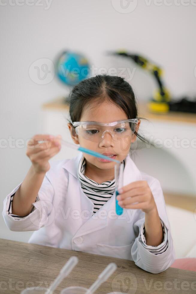 liten söt flicka med en mikroskop innehav en laboratorium flaska med vatten experimentera studie vetenskapsmän på skola. utbildning vetenskap begrepp. foto