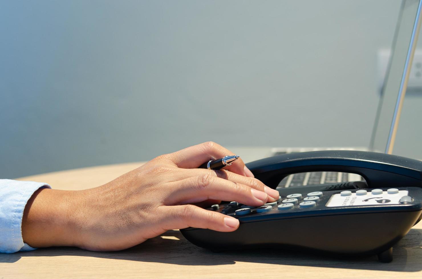 affärsman som håller en penna och trycker på telefonen vid skrivbordet foto