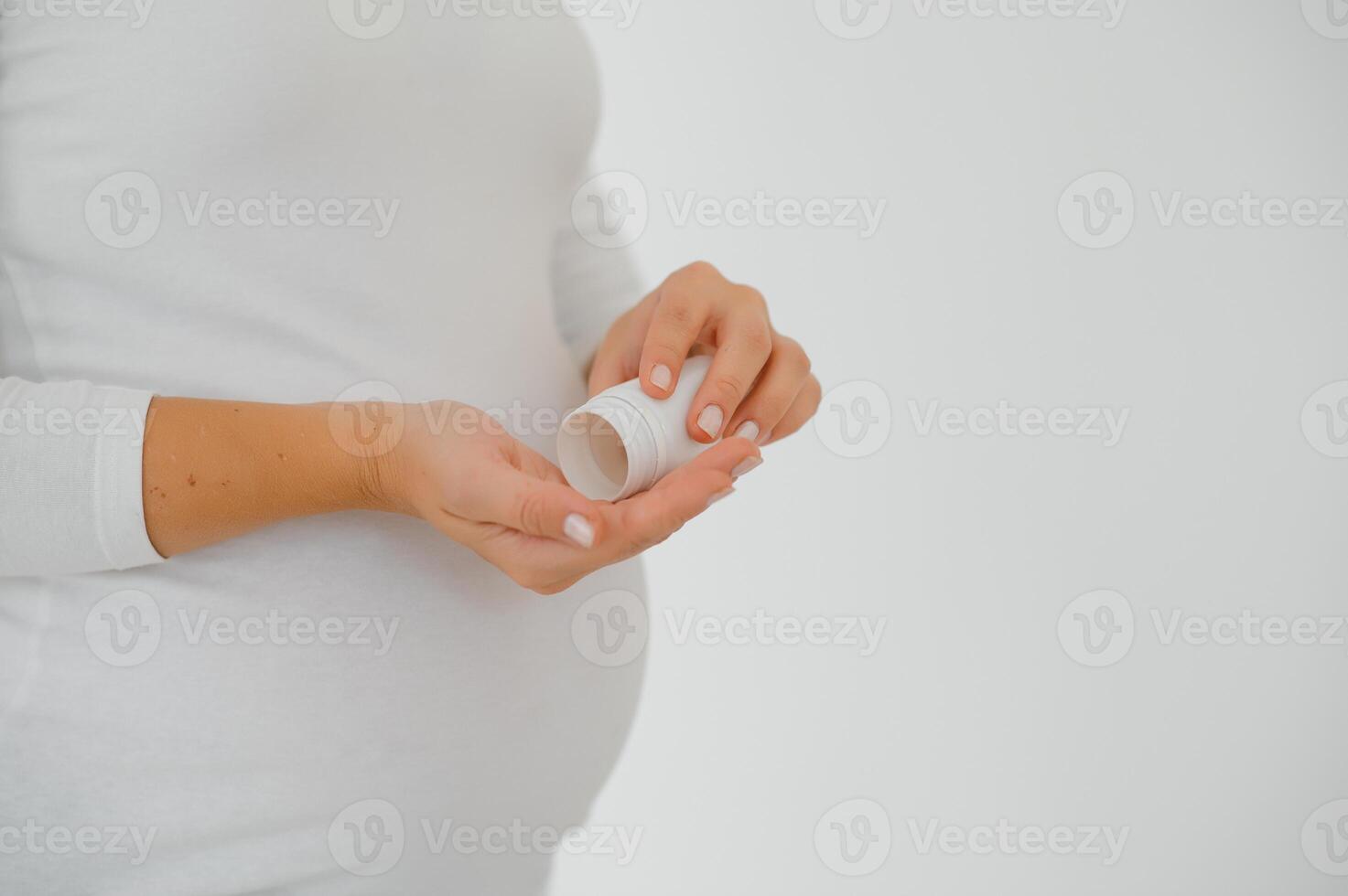 stänga upp på gravid mage med medicin..kvinna förväntar sig en bebis klädd i vit innehav piller. tar läkemedel eller vitaminer under graviditet begrepp. foto