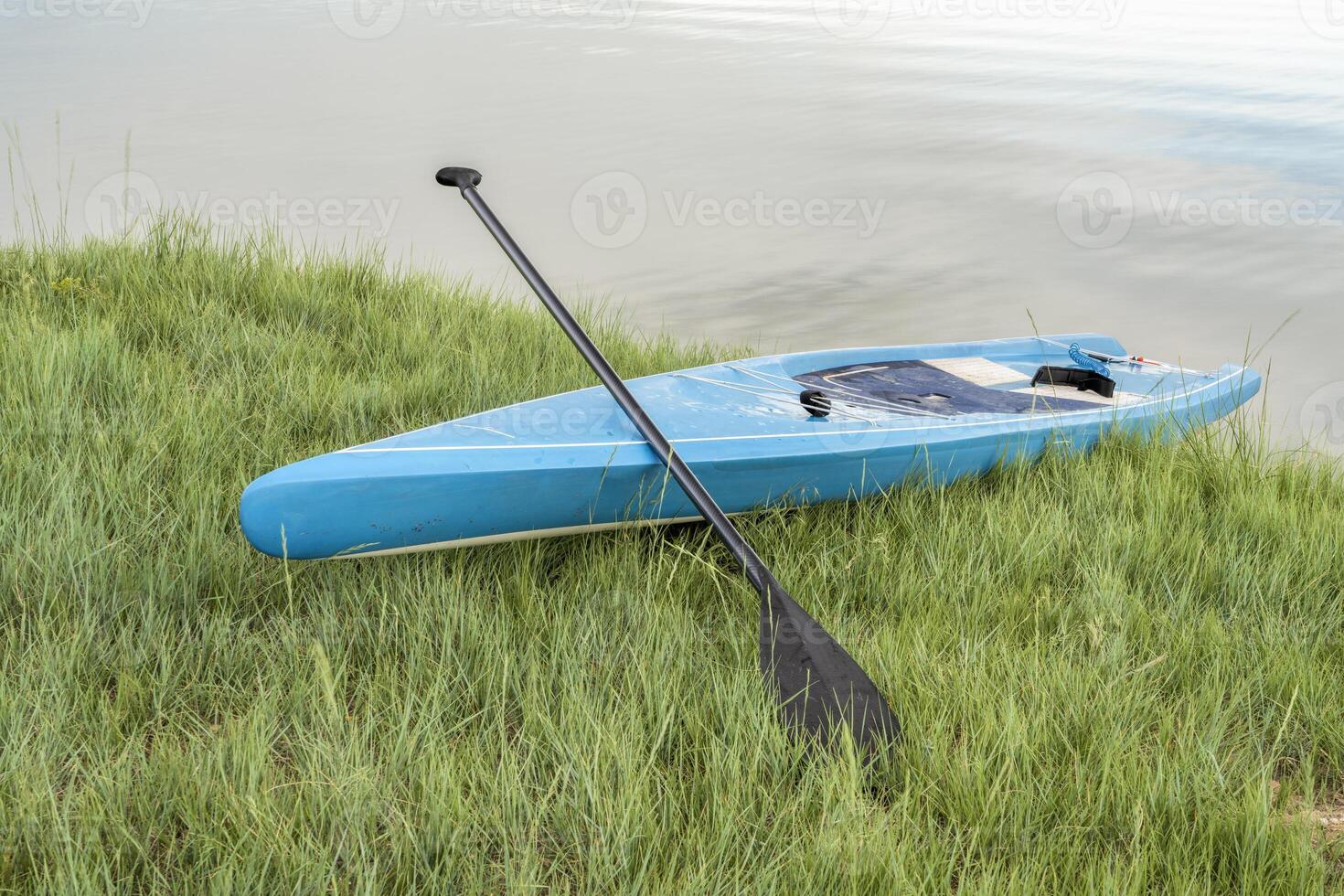 touring stå upp paddelbräda med en paddla på en gräs- sjö Strand foto