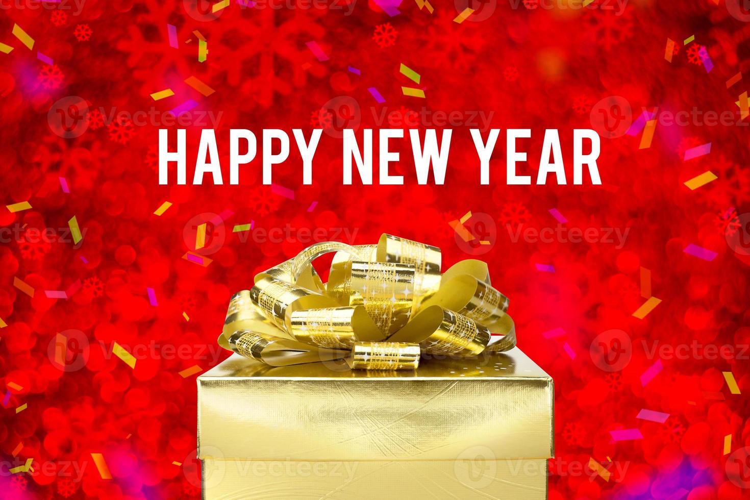 gott nytt år ord med gyllene presentask med band och färgglad konfetti vid oskärpa röd snöflinga boekh foto