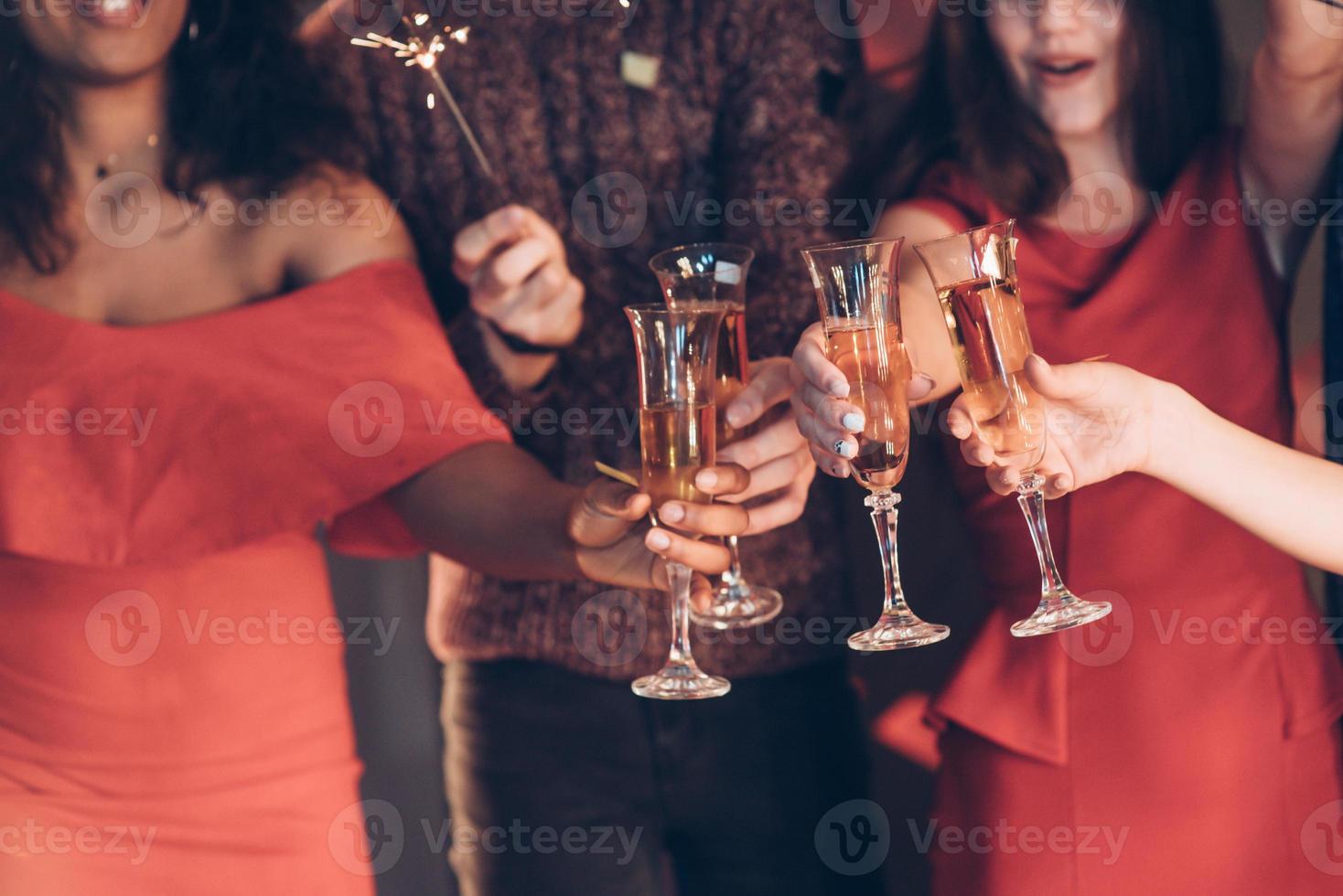 för vår framtid. multiracial vänner firar nyår och håller bengal lampor och glas med drink foto