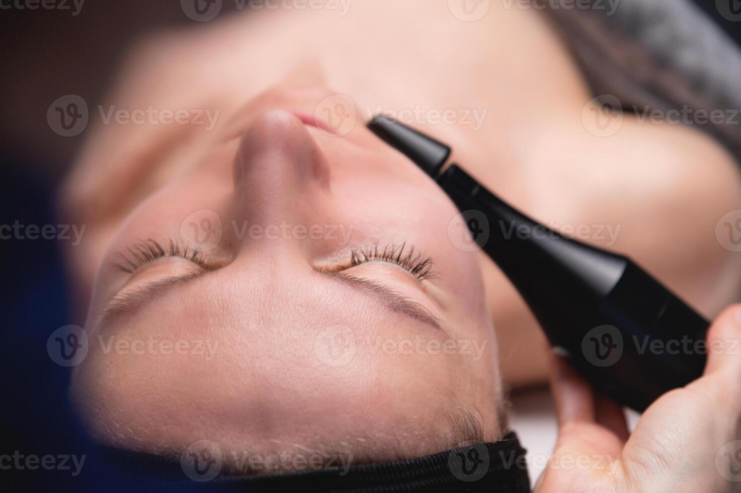 lymfatisk dränering massage är en hårdvara bearbeta. en kosmetolog-terapeut ger en modell en föryngrande ansiktsbehandling massage i en skönhet salong. närbild foto