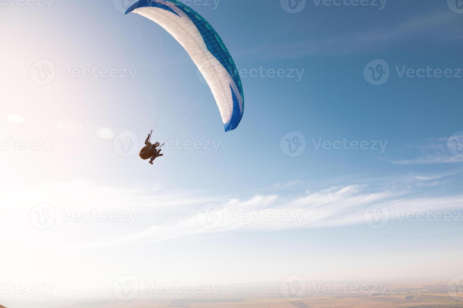 en paraglider med en blå fallskärm flyga. en manlig flyght på de himmel och hissar en paraglider in i de luft foto