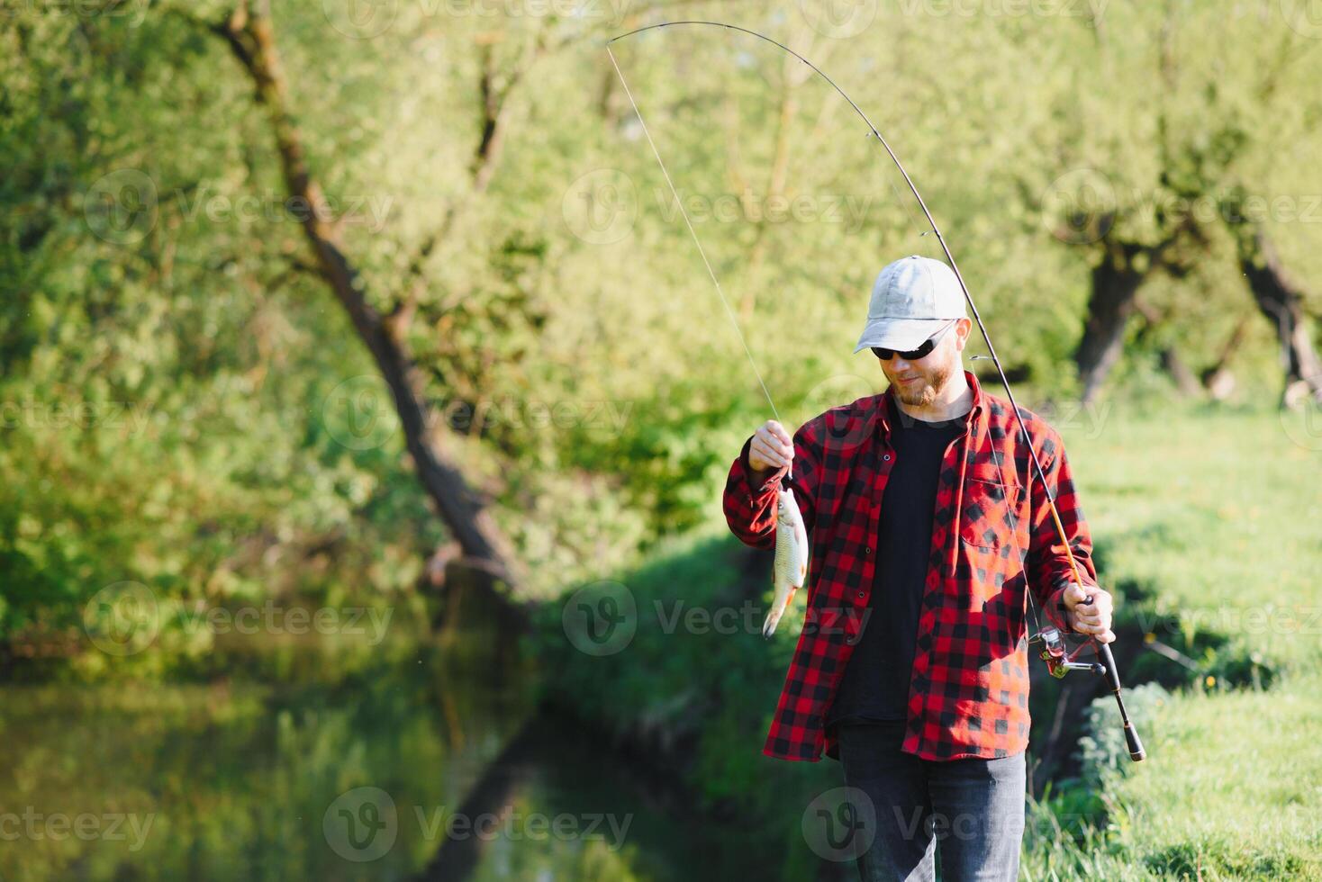 man avkopplande och fiske förbi sjön. helger tillverkad för fiske. fiskare maskulin hobby. bemästra baiter. ha kvar lugna och fisk på. fishman virkade snurra in i de flod väntar stor fisk. kille flyga fiske foto