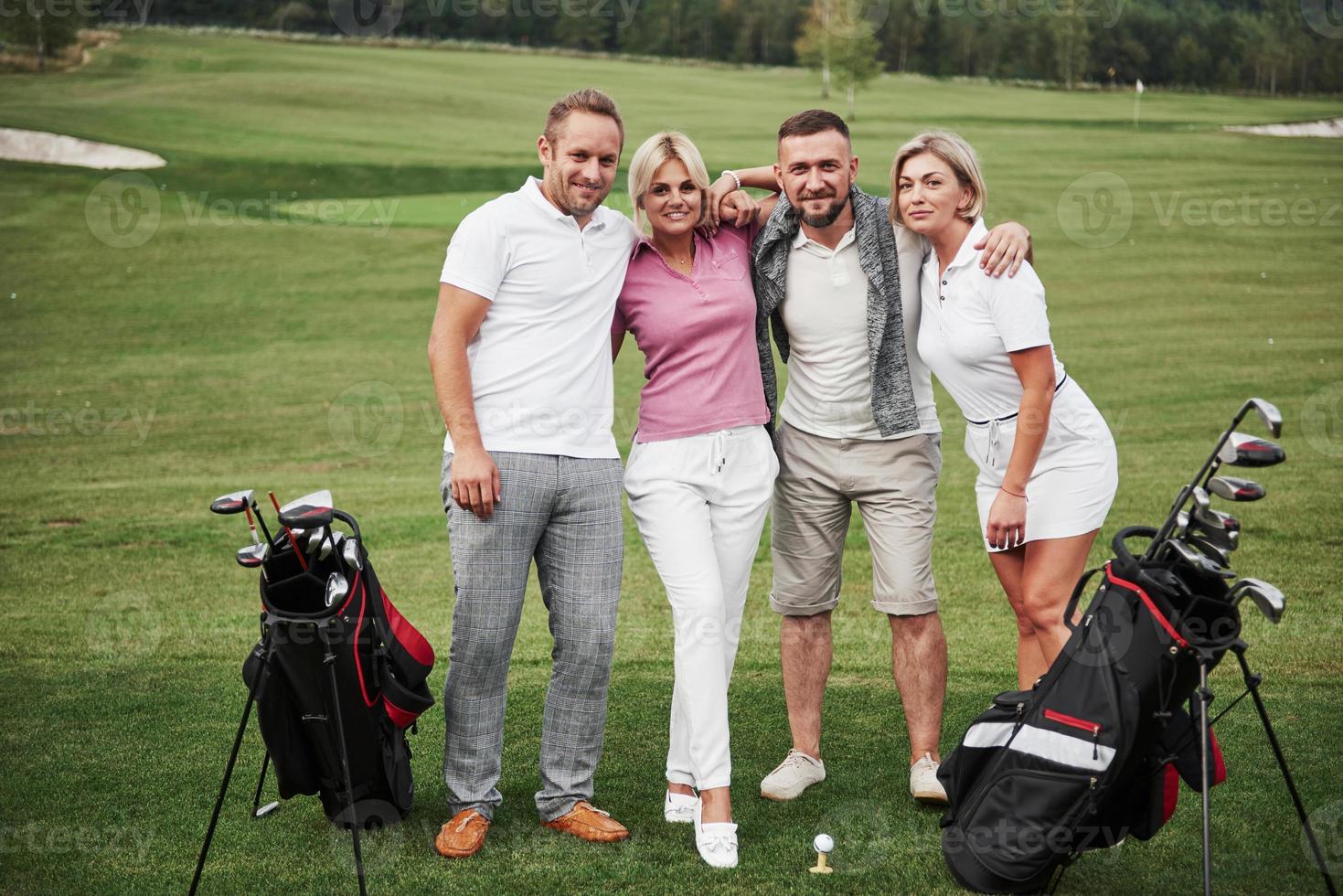 grupp snygga vänner på golfbanan lär sig spela ett nytt spel. laget ska vila efter matchen foto