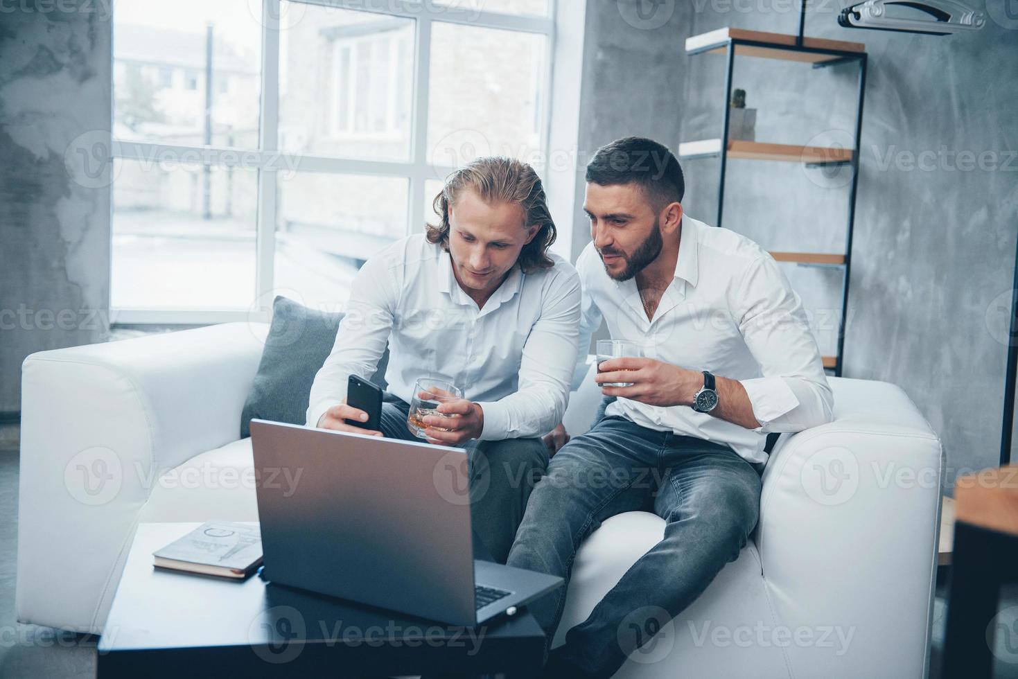 två affärsman sitter framför laptop talar om sina planer foto