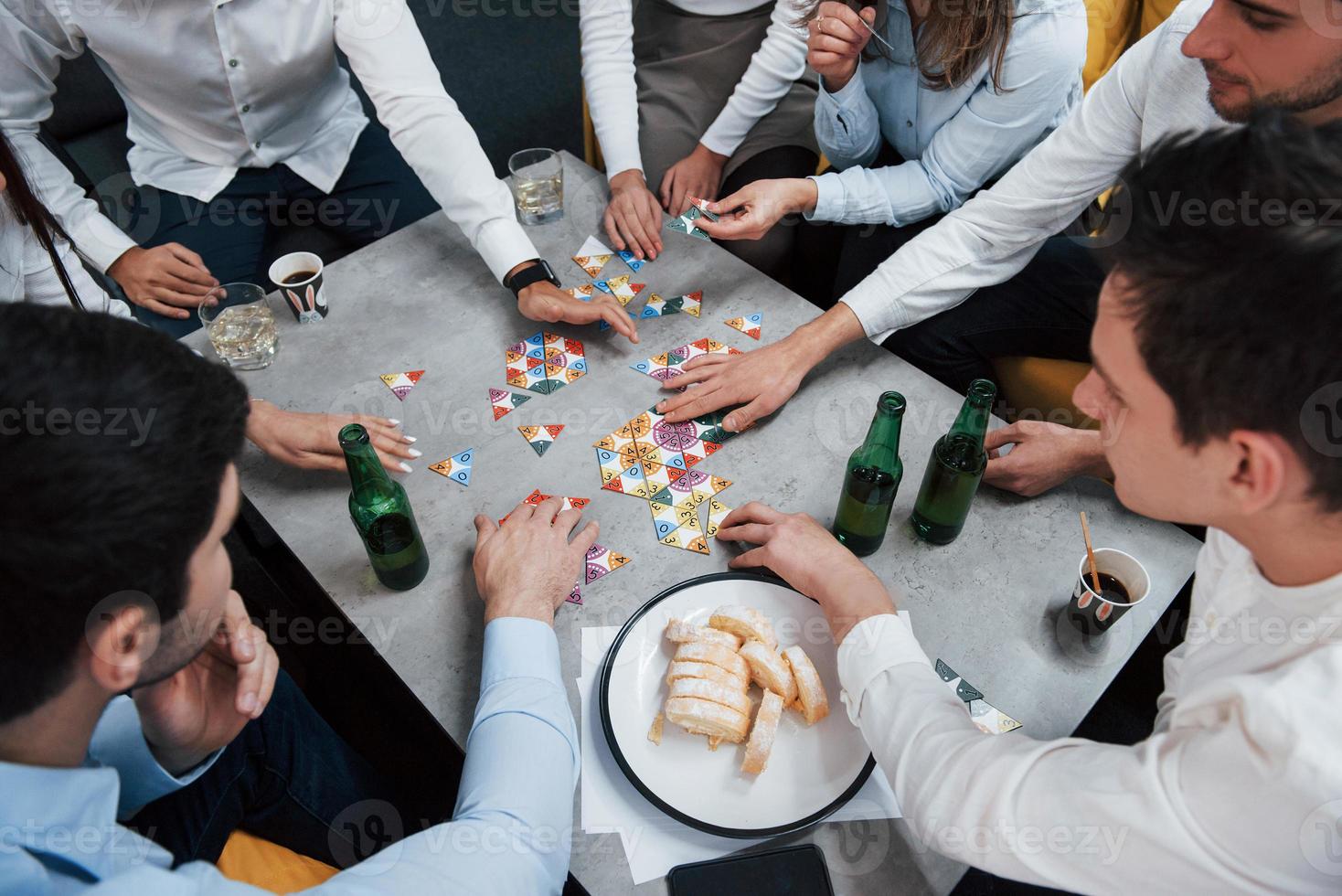 toppvy. koppla av med spel. firar framgångsrik affär. unga kontorsanställda som sitter nära bordet med alkohol foto