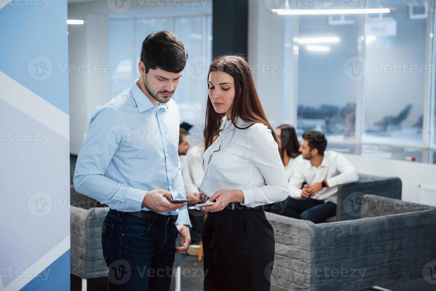 dela lite information. två kontorsarbetare i klassiska kläder som pratar inför anställda foto