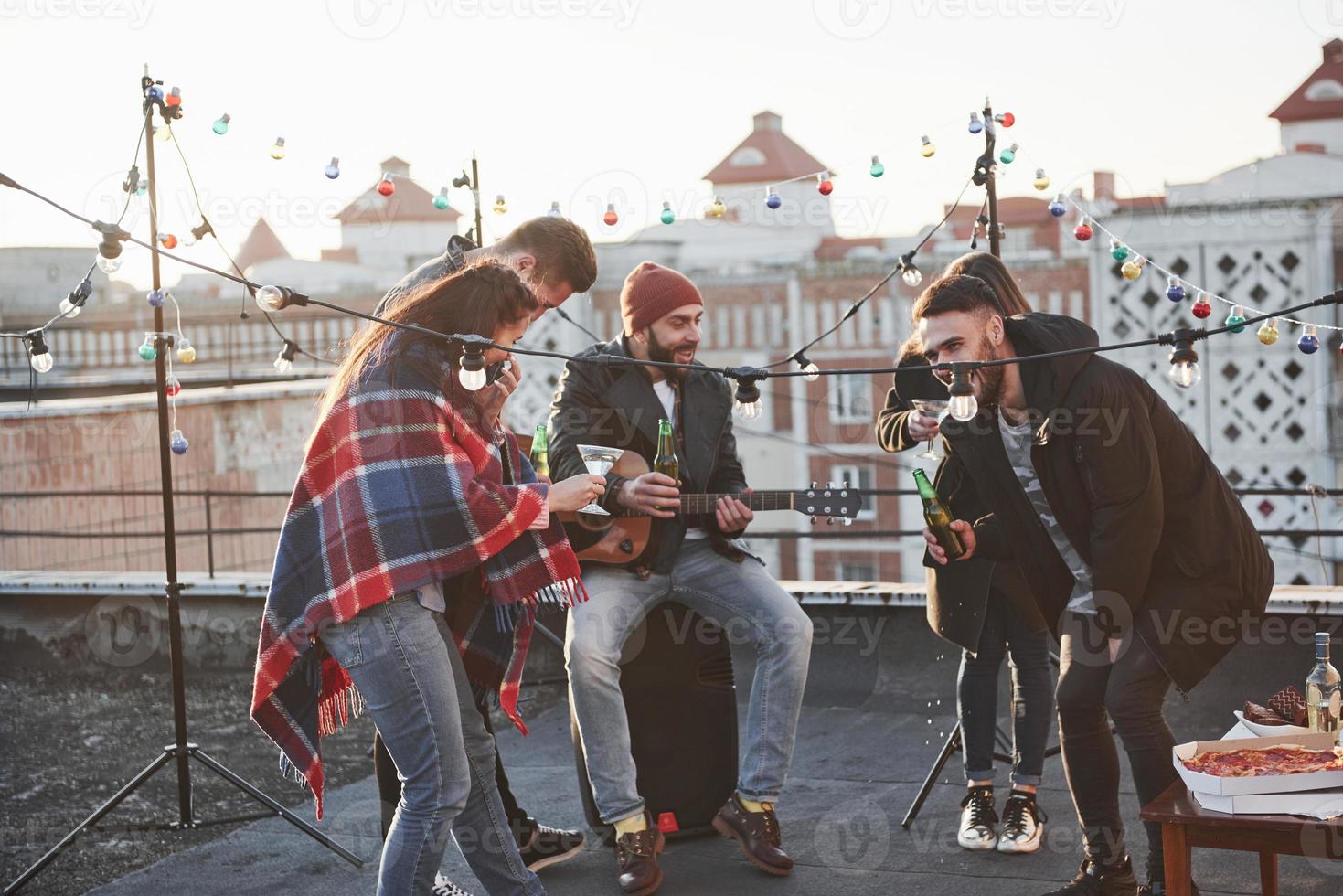 fem unga vänner festar med öl och gitarr på taket foto