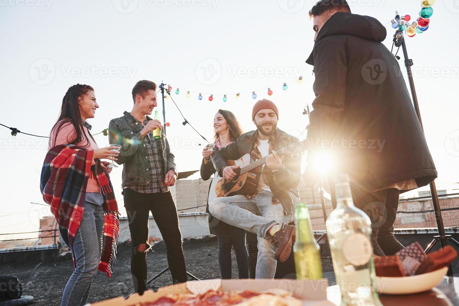 underbart solsken. bord med mat. helg på taket med gitarr, alkohol och pizza foto