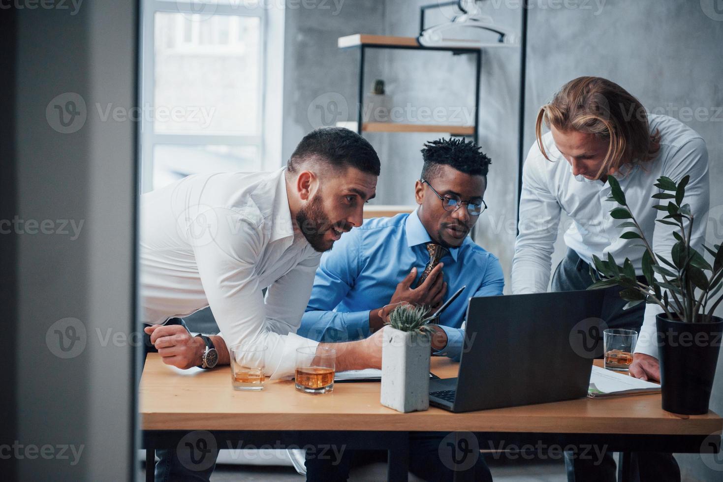 seriös man helt koncentrerad. multiracial affärsmän med laptop lösa företagets problem foto