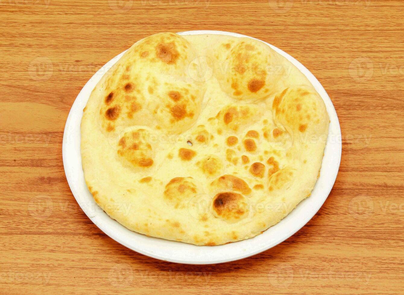 khamiri roti eller nan, nunna, roti, tandoori, chapati, pitabröd, bröd eras i en maträtt isolerat på trä- tabell sida se av indian, pakistansk mat foto